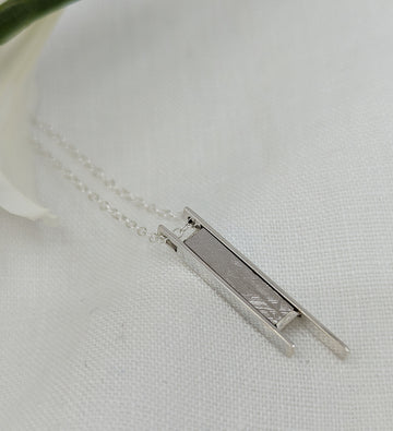 Long meteorite slice cased in long silver bar pendant
