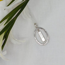 Load image into Gallery viewer, Long rectangular meteorite slice dangling within a silver oval pendant on a rope chain
