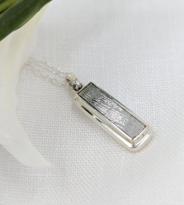 Long rectangular meteorite slice set in a double bezel silver setting as a pendant