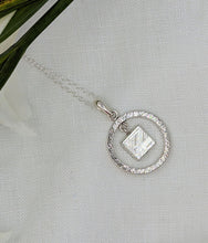 Load image into Gallery viewer, Square meteorite slice dangling within a silver circle pendant on a rope chain
