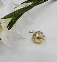 Load image into Gallery viewer, Large brass sphere encased with ornate silver detail as a pendant
