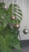 Load and play video in Gallery viewer, Large brass spheres encased with ornate silver detail as a pendants dangling on chains
