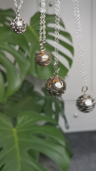 Large brass spheres encased with ornate silver detail as a pendants dangling on chains