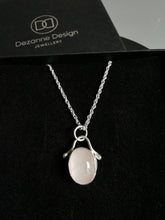 Load image into Gallery viewer, Polished oval rose quartz pendant with silver embellishment hanging on a silver rope chain
