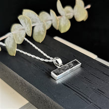 Load image into Gallery viewer, Meteorite slice set in a silver horizontal bar pendant on a rope chain
