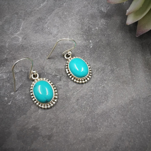 Bright turquoise ovals set in silver ornate dangle and drop earrings